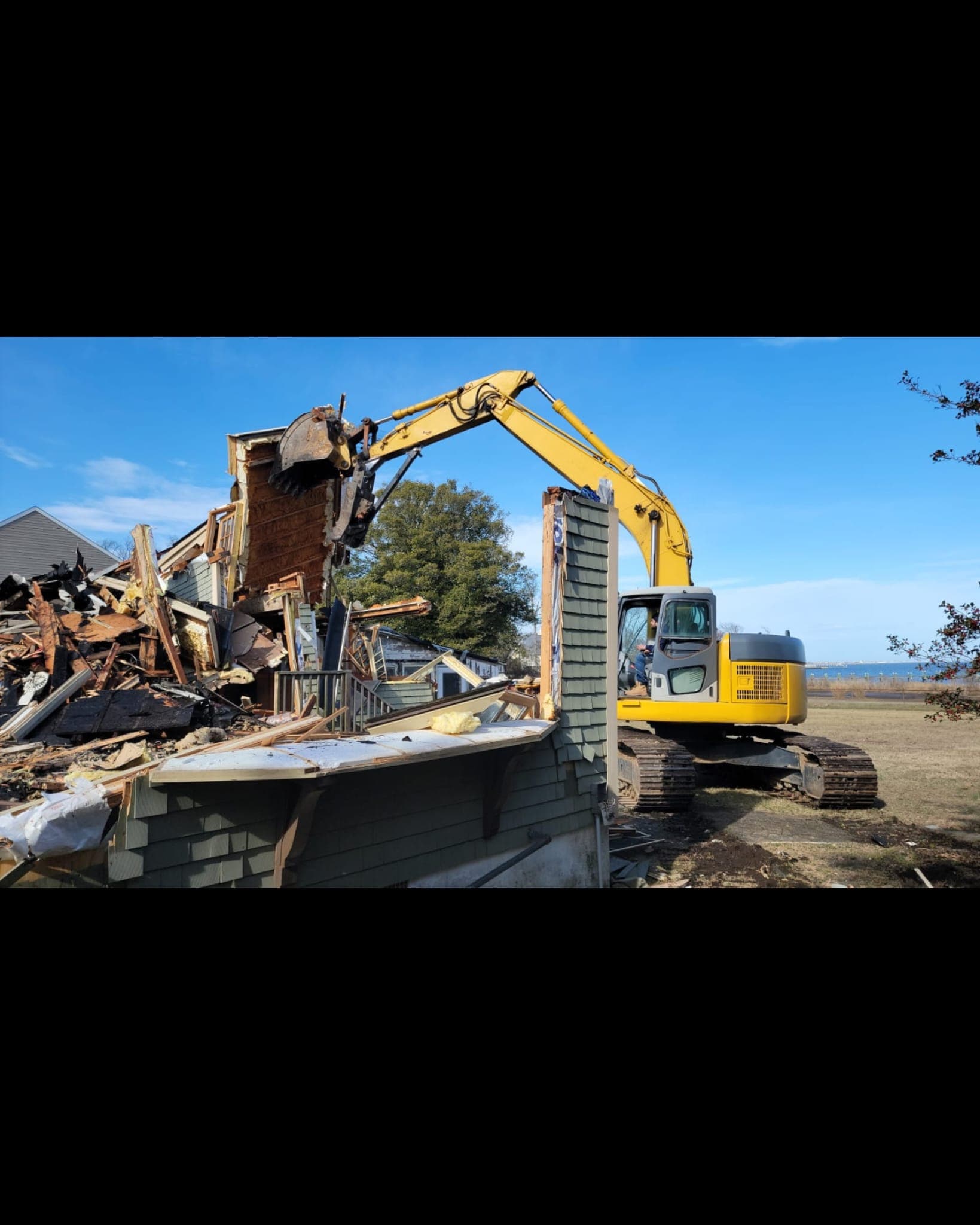excavator working near a house demolition site