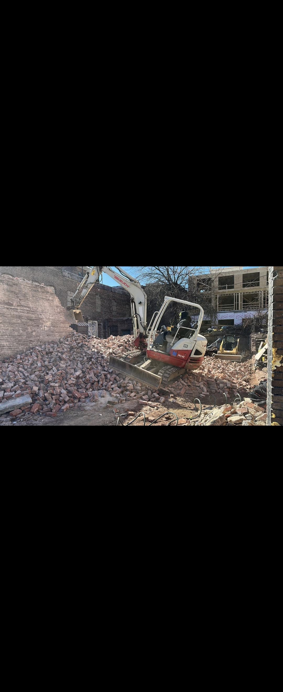 small excavator on active demo site on a hill